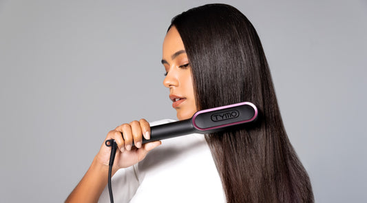 Woman using a professional hair straightening brush on her long, smooth hair, demonstrating effective styling for sleek results.