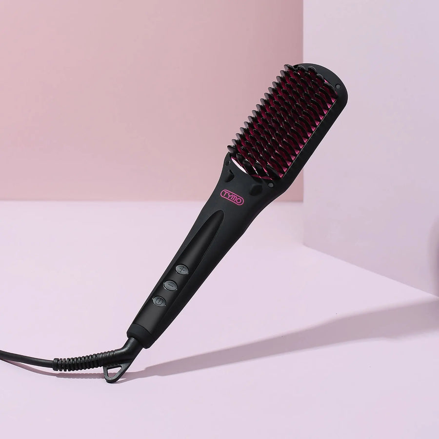 Close-up of TYMO iONIC hair straightener with its ergonomic, sleek design, set against a pink wall background.