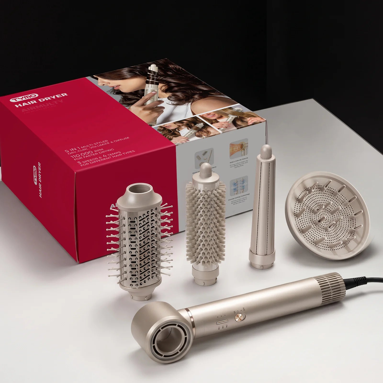 A salon hair dryer set displayed on a white surface with its red and white retail box behind it. The set includes a metallic silver hair dryer, three attachment nozzles, and a round concentrator nozzle.